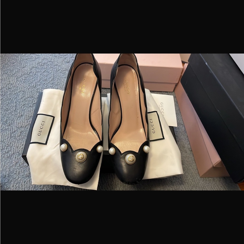 Black Gucci shoes with pearl detail .